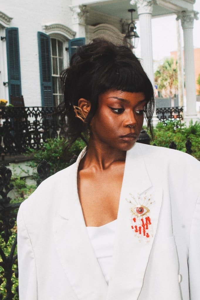 Blood & Tears brooch worn on a white blazer in front of historic West Palm Beach architecture