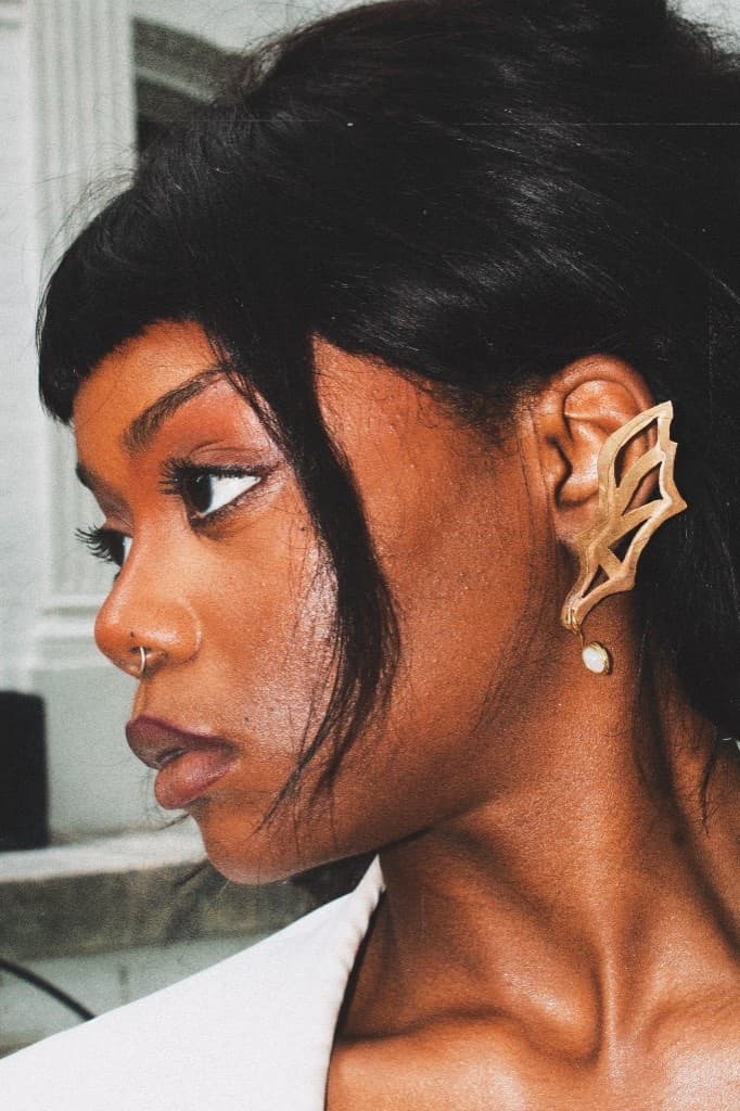 Profile close-up of the gold winged ear cuff with pearl drop