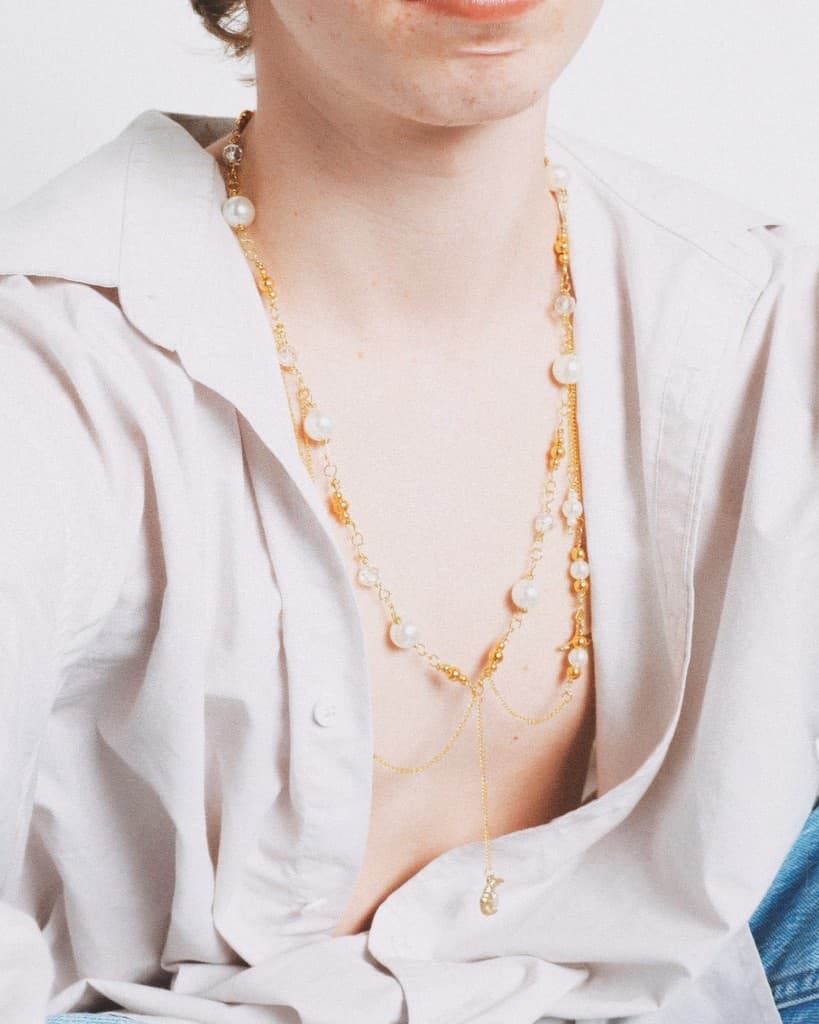 Close-up of the gold pearl swag necklace over a cream button-down