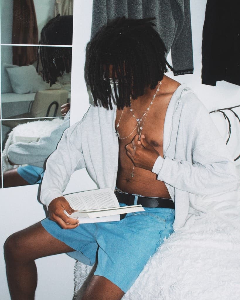 Reading on the bed beside a mirror wearing the layered necklace